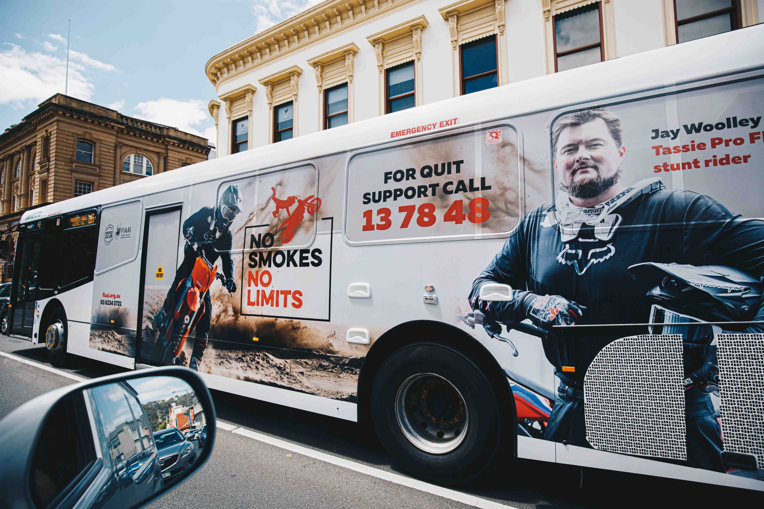 A No Smokes No Limits advertising campaign on the side of a metro bus, with MX rider Josh Woolley proudly smiling with support.