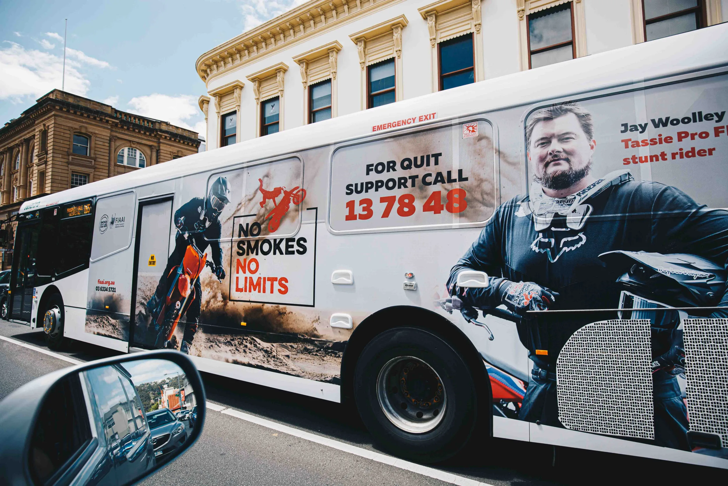 A No Smokes No Limits advertising campaign on the side of a metro bus, with MX rider Josh Woolley proudly smiling with support.